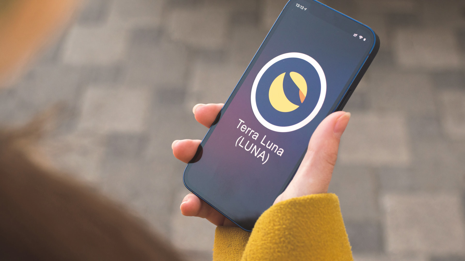 Terra Luna cryptocurrency symbol, logo. Business and financial concept. Hand with smartphone, screen with crypto icon closeup